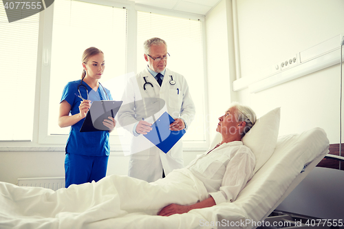 Image of doctor and nurse visiting senior woman at hospital