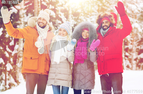 Image of group of friends waving hands in winter forest