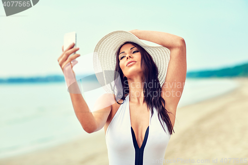 Image of smiling young woman taking selfie with smartphone