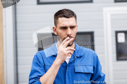 Image of auto mechanic smoking cigarette at car workshop