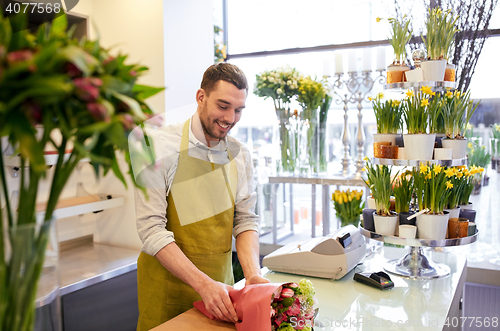 Image of florist wrapping flowers in paper at flower shop