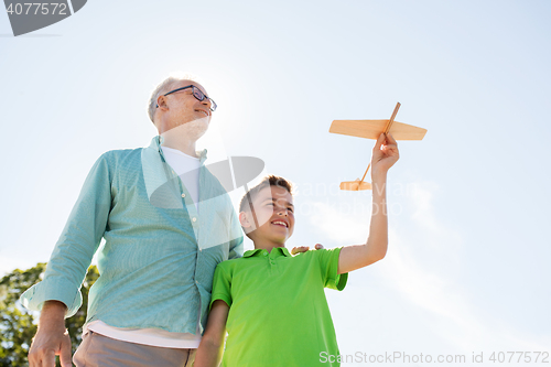 Image of senior man and boy with toy airplane over sky