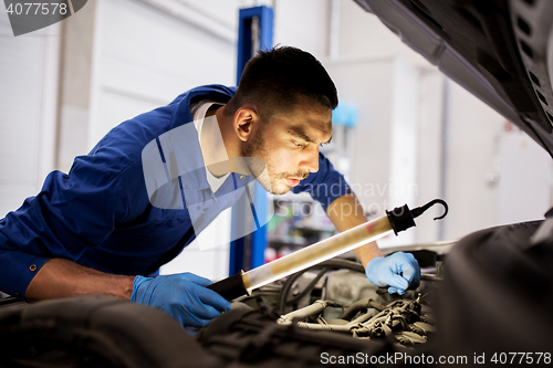 Image of mechanic man with lamp repairing car at workshop