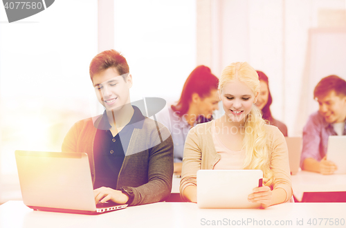 Image of two smiling students with laptop and tablet pc