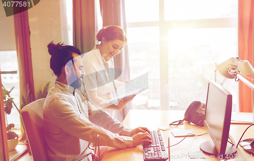 Image of happy creative team with computer in office