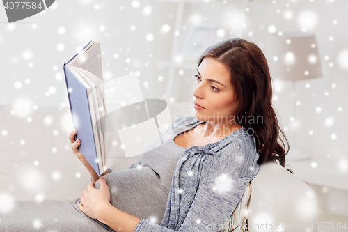 Image of pregnant woman reading book at home