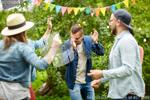 Image of happy friends dancing at summer party in garden