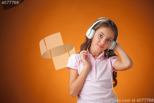 Image of The cute cheerful little girl on orange background