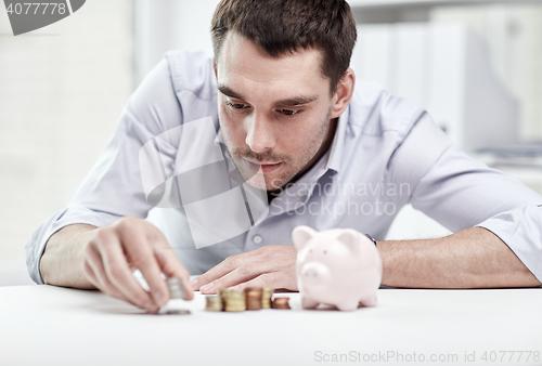 Image of businessman with piggy bank and coins at office