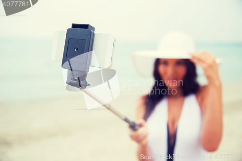 Image of smiling young woman taking selfie with smartphone