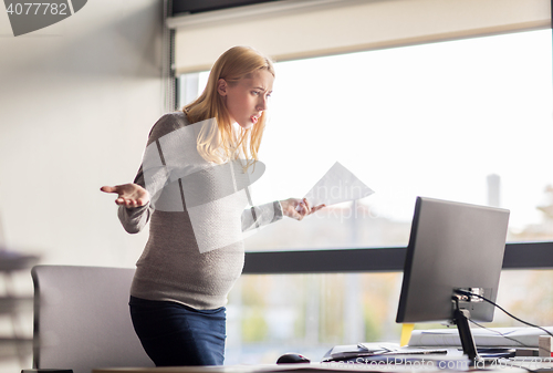 Image of pregnant businesswoman stressing at office work