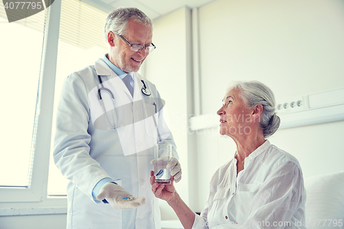 Image of doctor giving medicine to senior woman at hospital