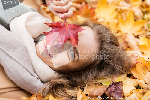 Image of beautiful happy woman lying on autumn leaves