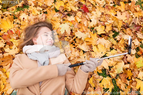 Image of woman on autumn leaves taking selfie by smartphone