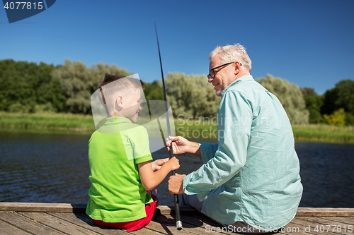 Image of grandfather and grandson fishing on river berth