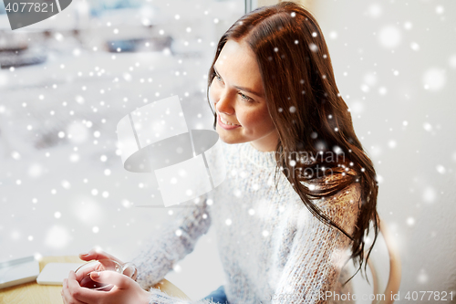 Image of smiling young woman drinking tea at cafe