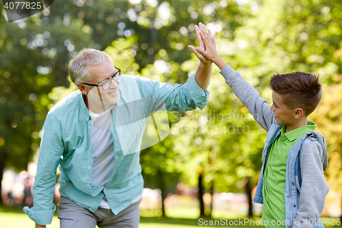 Image of old man and boy making high five at summer park