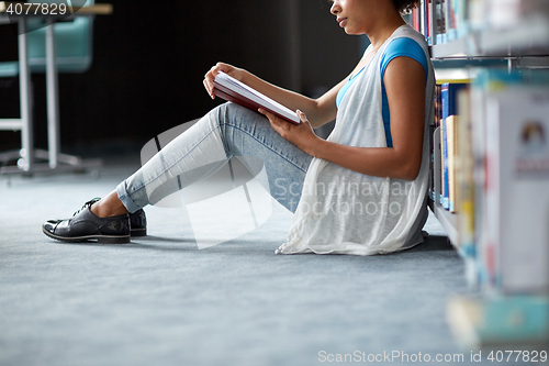 Image of happy african student girl reading book at library