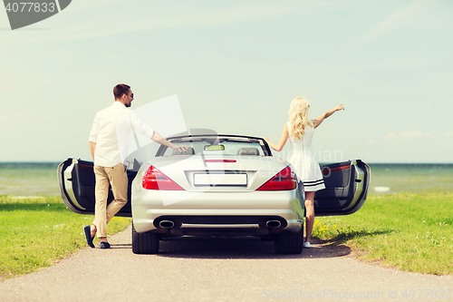 Image of happy man and woman near cabriolet car at sea