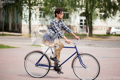 Image of young hipster man with bag riding fixed gear bike