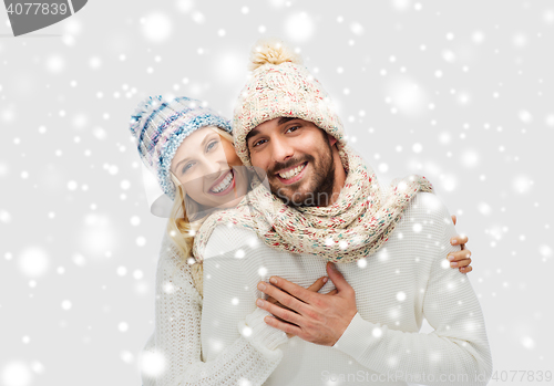 Image of smiling couple in winter clothes hugging over snow