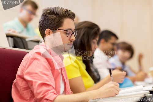 Image of group of students with notebooks in lecture hall