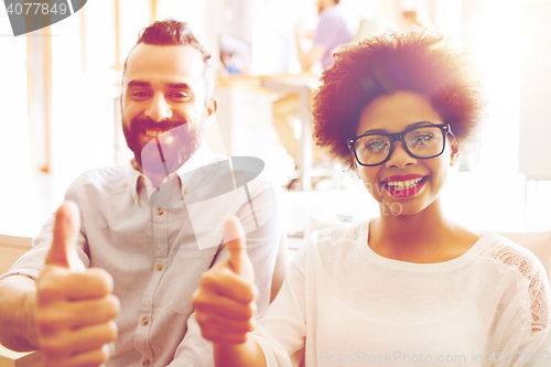 Image of happy creative team in office showing thumbs up