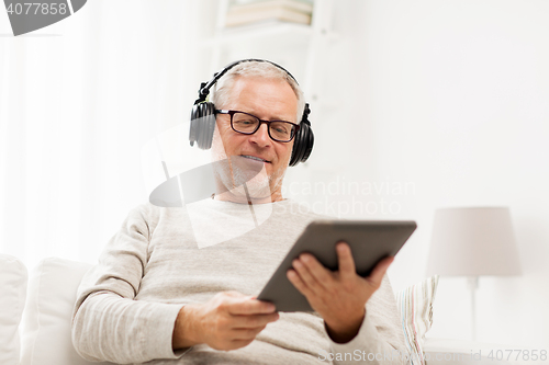 Image of senior man with tablet pc and headphones at home