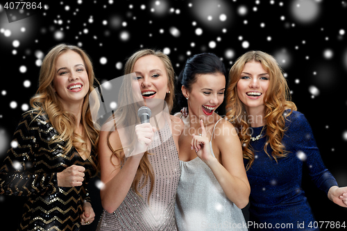 Image of happy young women with microphone singing karaoke