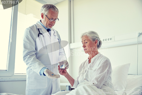 Image of doctor giving medicine to senior woman at hospital