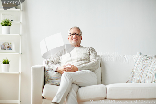 Image of smiling senior man in glasses sitting on sofa