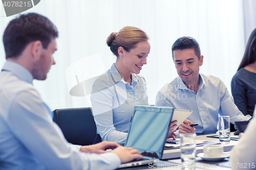 Image of smiling business people with tablet pc in office