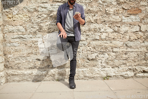 Image of close up of man with smartphone at stone wall