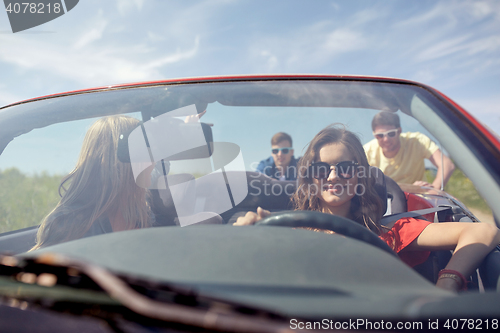 Image of happy friends pushing broken cabriolet car