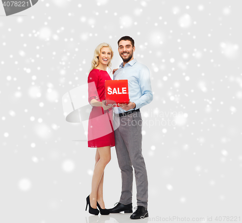 Image of happy couple with red sale sign over snow