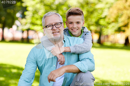 Image of grandfather and grandson hugging at summer park