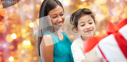 Image of happy mother and girl with gift box over lights