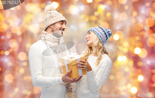 Image of smiling couple in winter clothes with gift box