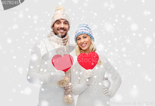 Image of smiling couple in winter clothes with red hearts