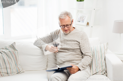 Image of happy senior man drinking wine and reading book