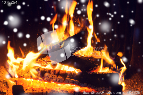 Image of close up of firewood burning in fireplace and snow