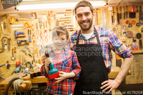 Image of father and son with drill working at workshop