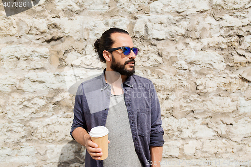 Image of man drinking coffee from paper cup on street