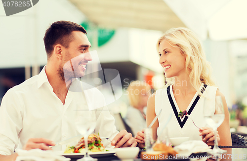 Image of happy couple eating dinner at restaurant terrace