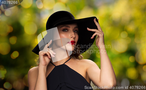 Image of beautiful woman in black hat over dark background
