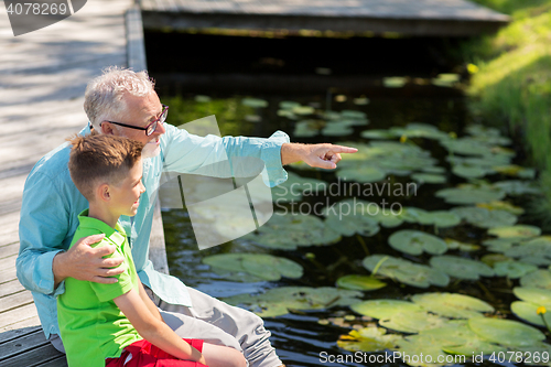 Image of grandfather and grandson sitting on river berth