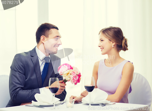 Image of smiling man giving flower bouquet at restaurant