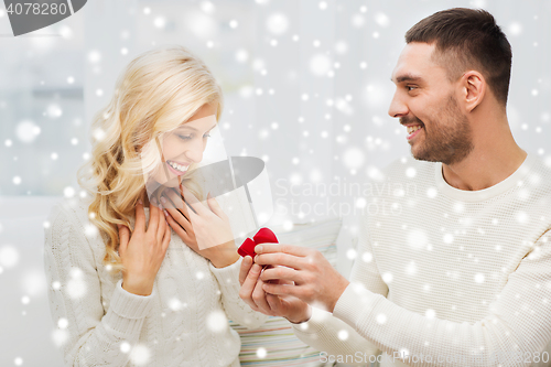 Image of happy man giving engagement ring to woman at home