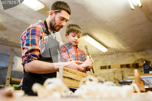 Image of father and son with chisel working at workshop