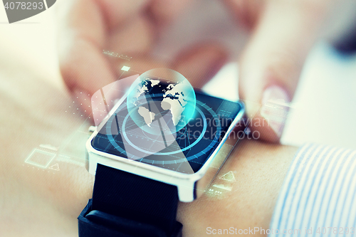 Image of close up of hand with globe hologram on smartwatch